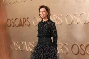 Uma mulher sorridente está posando em frente a uma parede com a palavra