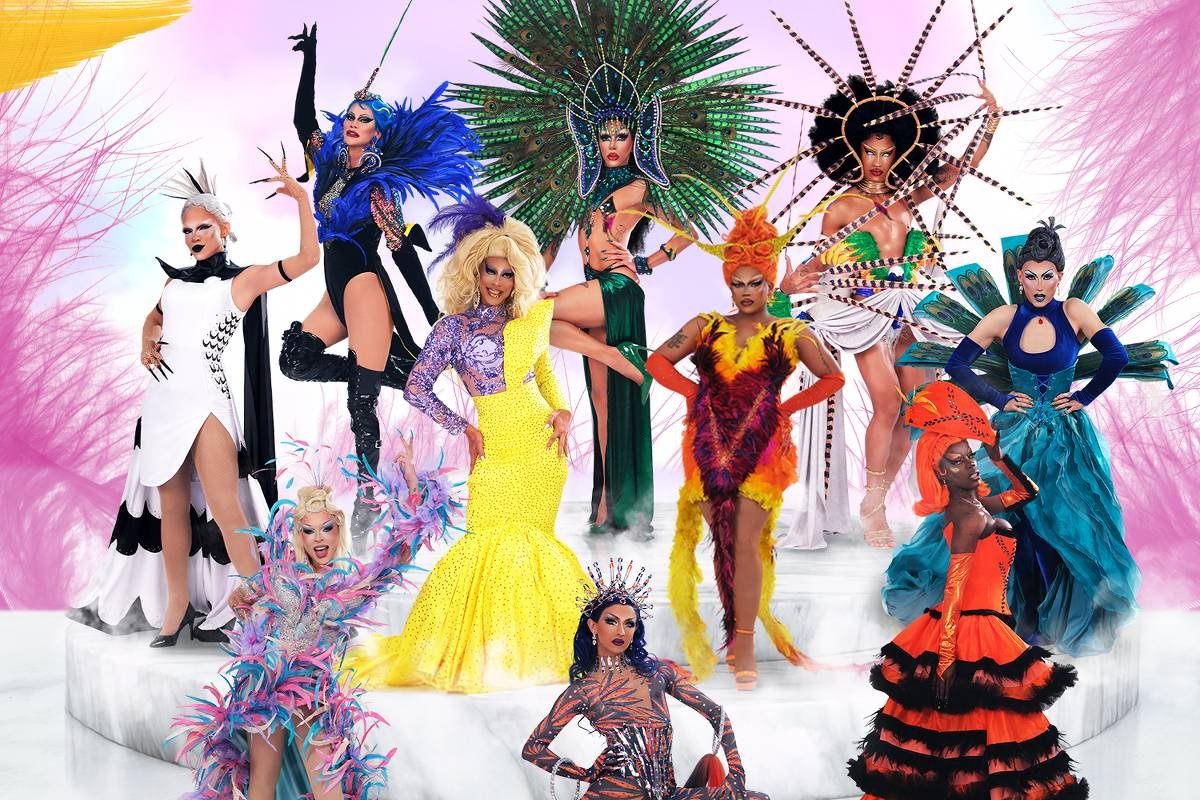 A imagem apresenta um grupo de drag queens em um cenário vibrante e colorido. Elas estão vestidas com trajes elaborados e extravagantes, cada uma com um estilo único. O fundo é decorado com elementos festivos e coloridos, criando uma atmosfera de celebração. No topo da imagem, está o título