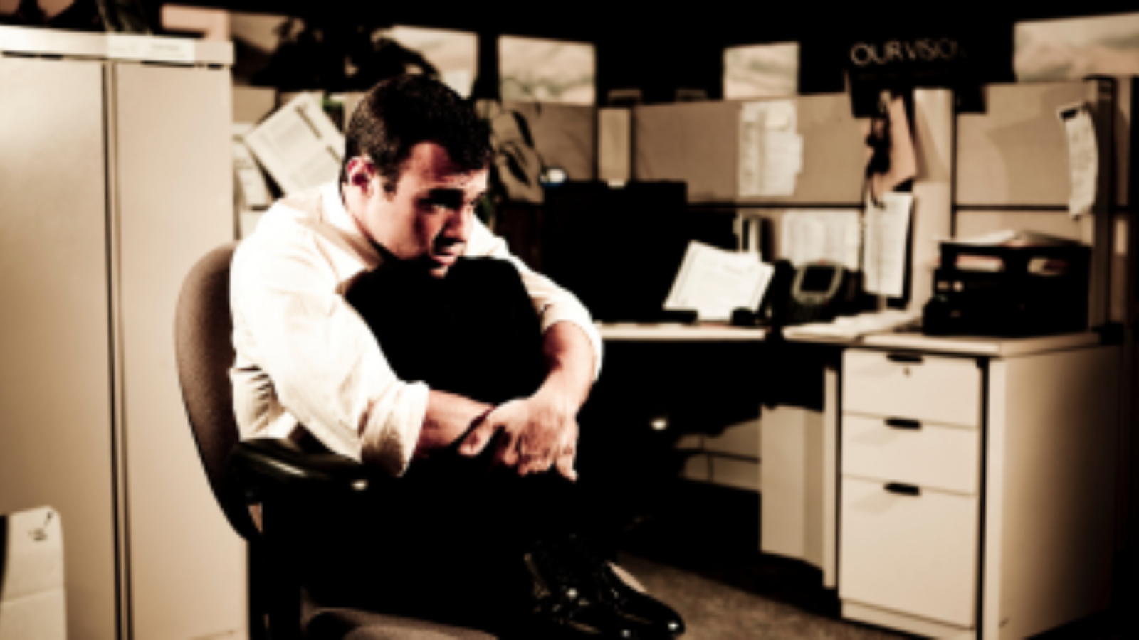 Homem sentado em ambiente corporativo, com postura retraída e expressão de preocupação, representando insegurança diante de mudanças no trabalho